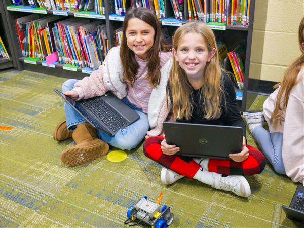 two girls smiling with computer